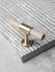 SIGNATURE slim T-bar 54 mm in Brushed Brass/Oak. Modern kitchen hardware made of solid brass by BRANDT Collective.