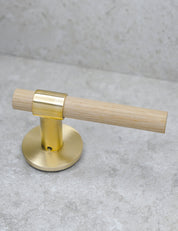 SIGNATURE door handle in Brushed Brass/Oak. Modern door hardware made of solid brass by BRANDT Collective.